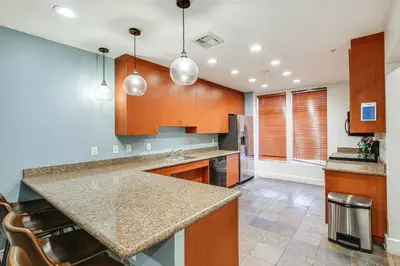 a kitchen with wooden cabinets and a counter top at Luxe Long Beach Condo with Pool 1 Mi to Shoreline! in Long Beach