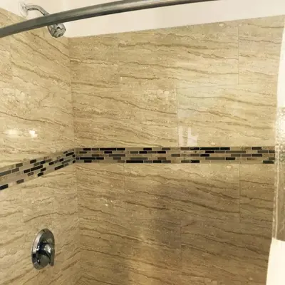 a bathroom with a shower with a beige and black tile at Crenshaw Inn Motel in Los Angeles