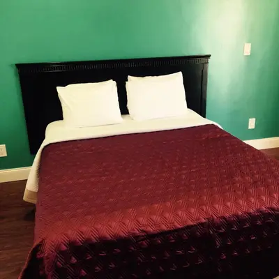 a bed with a red comforter and two pillows at Crenshaw Inn Motel in Los Angeles