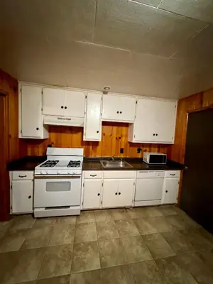 a kitchen with white cabinets and a stove and a sink at Crest Lodge Historic Mountain Inn in Crestline