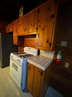 a kitchen with a stove and wooden cabinets at Crest Lodge Historic Mountain Inn in Crestline