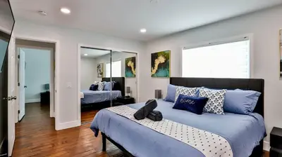 a bedroom with a large bed with blue pillows at H&H Modern Lux 4BD 1 King Suite 3 Queen SoCal Disney in Westminster