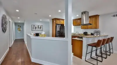 a kitchen with a counter and a bar with stools at H&H Modern Lux 4BD 1 King Suite 3 Queen SoCal Disney in Westminster