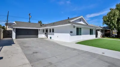 a white house with a garage and a green lawn at H&H Modern Lux 4BD 1 King Suite 3 Queen SoCal Disney in Westminster