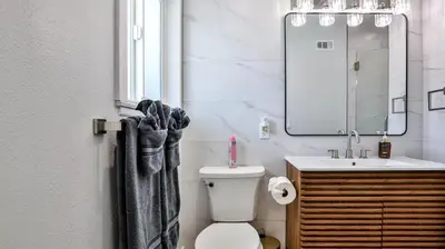 a bathroom with a toilet and a sink and a mirror at H&H Modern Lux 4BD 1 King Suite 3 Queen SoCal Disney in Westminster