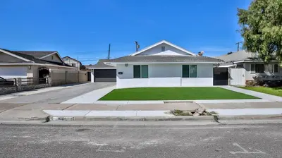 a white house with a green lawn in front of it at H&H Modern Lux 4BD 1 King Suite 3 Queen SoCal Disney in Westminster