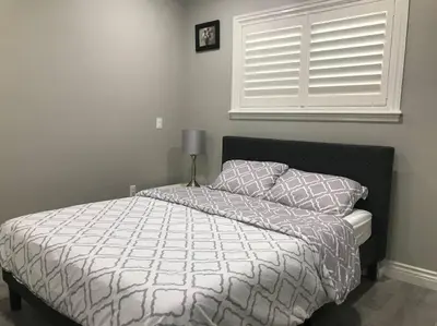 a bedroom with a bed with a white comforter and a window at New! Modern Gated Summer Getaway Home in Rosemead