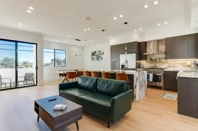 a living room and kitchen with a couch and a table at Brand New Modern 9 Bedroom Compound in Pickfair Village in Los Angeles
