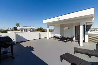 a patio with chairs and tables on the roof of a house at Brand New Modern 9 Bedroom Compound in Pickfair Village in Los Angeles