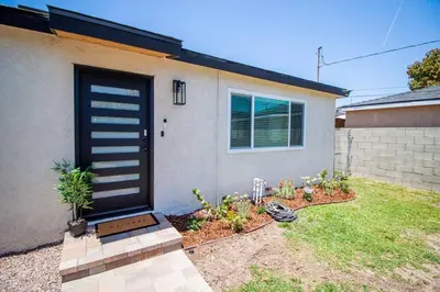 a house with a black door and some plants at Comfortable & Modern 3BD/2BA Home -pet friendly! in Lawndale