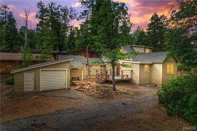 a large house with a garage and a tree at Warbler's Roost - Perfect vintage cabin in the woods in Big Bear Lake