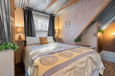 a bedroom with a large bed and a window at Warbler's Roost - Perfect vintage cabin in the woods in Big Bear Lake