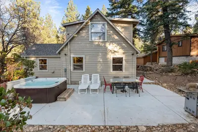 a backyard with a hot tub and a table and chairs at Warbler's Roost - Perfect vintage cabin in the woods in Big Bear Lake