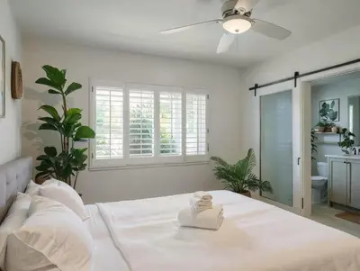 a white bedroom with a bed and a ceiling fan at Private Pool Retreat Near Disney Game Room & Firepit in Fullerton