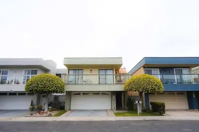 an apartment building with a balcony and two trees at SeaView, Pool, HotTub, W/D, Bikes, Gated Community in Port Hueneme