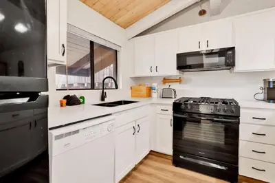 a kitchen with white cabinets and a black stove top oven at Chairlift Lodge Bg Bear~ Walk to Lift Condo~ in Big Bear Lake