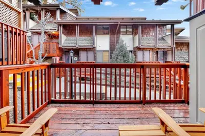 a wooden deck with two chairs and a house at Chairlift Lodge Bg Bear~ Walk to Lift Condo~ in Big Bear Lake