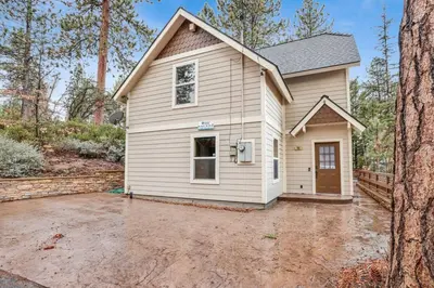 a small white house with a driveway at Mount Berkley Big Bear~ Walk to Village~ Games~ in Big Bear Lake
