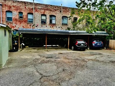 a garage with two cars parked in front of a brick building at Walk To Americana on Brand. in Glendale