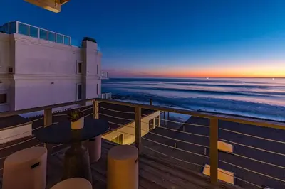 a balcony with a table and the ocean at sunset at Malibu Best Kept Secret in Malibu
