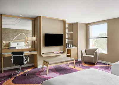 a hotel room with a bed and a tv and a chair at Pasadena Hotel & Pool in Pasadena