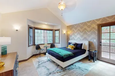 a bedroom with a bed and a desk and windows at The Chateau in Lake Arrowhead
