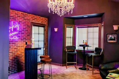 a bar with purple walls and stools and a chandelier at The Chateau in Lake Arrowhead