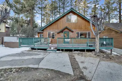 a log house with a green fence in front of it at Big Bear Happy Place~ Hot Tub~ Games~ Walk to Village~ in Big Bear Lake