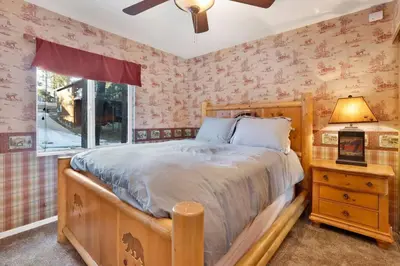 a bedroom with a wooden bed and a window at Big Bear Happy Place~ Hot Tub~ Games~ Walk to Village~ in Big Bear Lake