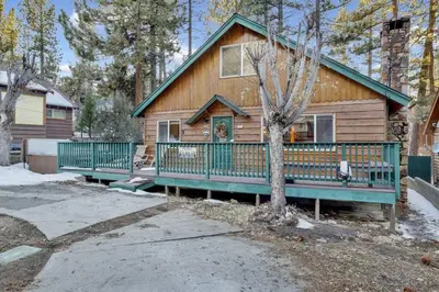 a log cabin with a porch and a tree at Big Bear Happy Place~ Hot Tub~ Games~ Walk to Village~ in Big Bear Lake