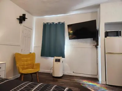 a bedroom with a bed and a refrigerator and a chair at Eight Street Apartments in Long Beach