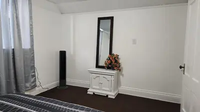 a bedroom with a mirror on a white wall at Eight Street Apartments in Long Beach