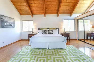 a bedroom with a bed and two tables and windows at Large 5 BR- Beverly Hills Adj in Los Angeles