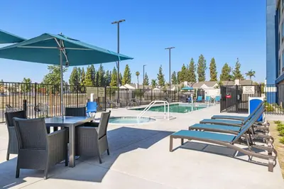 a patio with a table and chairs and a pool at Hampton Inn & Suites Bakersfield Central in Bakersfield
