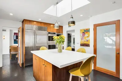 a kitchen with a white counter and yellow chairs at Edwin by AvantStay Hollywood Hills Luxury Pool in Los Angeles
