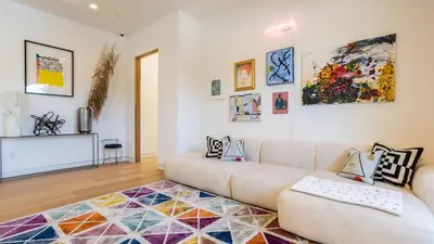 a living room with a couch and paintings on the wall at Luxe WeHo Villa Walk to Melrose Ave Pool Hot Tub North Vista by AvantStay in Los Angeles
