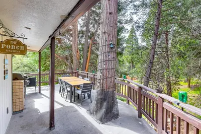 a porch with a table and chairs and a tree at Crestline Home with Private Hot Tub Steps to Lake! in Crestline