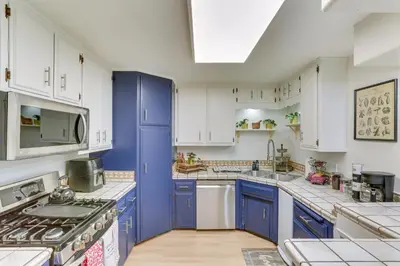 a blue and white kitchen with white cabinets at Crestline Home with Private Hot Tub Steps to Lake! in Crestline