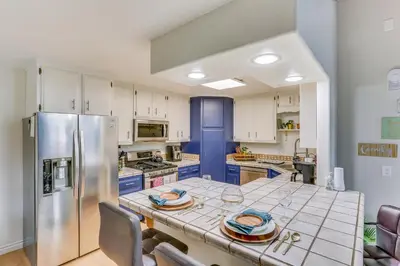 a kitchen with a table and a refrigerator at Crestline Home with Private Hot Tub Steps to Lake! in Crestline
