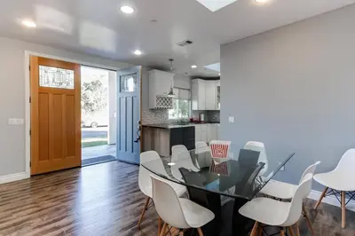 a kitchen and dining room with a glass table and white chairs at Lake Balboa 7 Bedroom 5 Bathroom Compound in Los Angeles