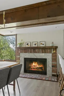 a fireplace in a living room with a table and chairs at Lake Reflection Point Upscale Lake House 4 Bed and 4.5 Bath in Lake Arrowhead