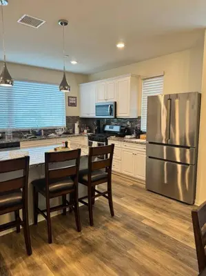 a kitchen with a refrigerator and a table with chairs at 3 Bedroom Townhome with Large Living Area in Downey