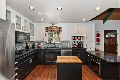 a kitchen with white cabinets and black counter tops at Large Comfy Family cabin-Great Kitchen, Pool Table, Pets welcome in Lake Arrowhead