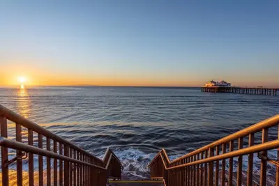a view of the ocean with a pier at sunset at Malibu Sand Carbon Beach Suites in Malibu