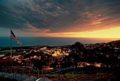 an american flag flying over a town at sunset at Villa Graziadio Executive Center at Pepperdine University in Malibu