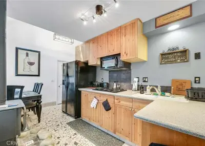 a kitchen with wooden cabinets and a black refrigerator at Merri Bear in Big Bear Lake