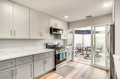 a kitchen with white cabinets and a view of a patio at Rental with Pool Access about 8 Mi to Disneyland in La Palma