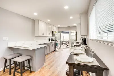 a kitchen with white cabinets and a table and chairs at Rental with Pool Access about 8 Mi to Disneyland in La Palma
