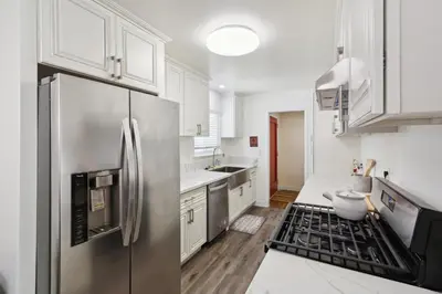 a kitchen with white cabinets and a stainless steel refrigerator at Modern Relaxing Retreat with Private Pool home in Azusa