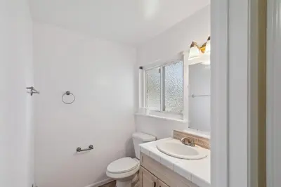 a white bathroom with a sink and a toilet at Modern Relaxing Retreat with Private Pool home in Azusa